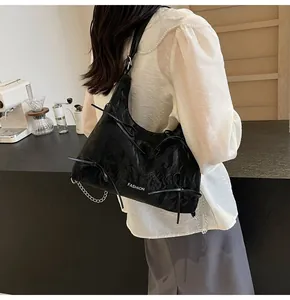 Détail d'un sac à bandoulière en cuir noir avec nœuds décoratifs et chaîne argentée