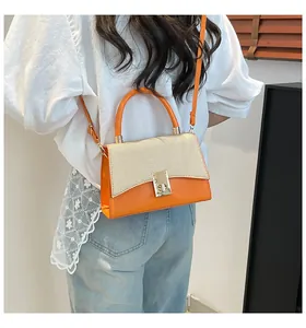 Detail of a color-block handbag with orange leather and beige woven flap and gold clasp