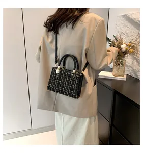 Sac bandoulière en tweed noir et doré porté par un mannequin en costume beige élégant