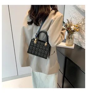 Détail de la texture en tweed noir et doré du sac bandoulière avec finitions dorées