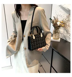 Détail du sac bandoulière en tweed noir avec poignée métallique dorée et texture