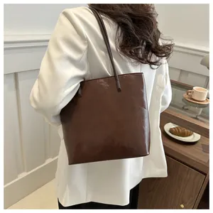 Detailed side view of a large dark brown leather tote bag on a woman's shoulder