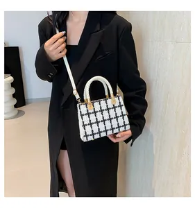 Vue détaillée du sac bandoulière en tweed noir et blanc avec poignées et accents dorés