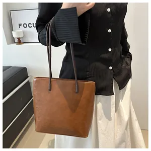 Detail view of large dark brown leather tote bag worn on shoulder by a model