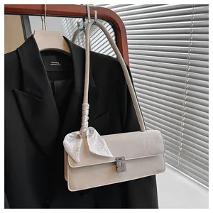 Détail d'un sac sous le bras crème avec boucle en strass et foulard en soie décoratif