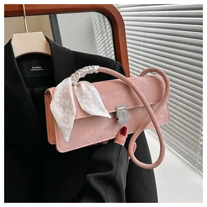 Détail du sac à main rose en daim avec boucle en strass et foulard en soie décoratif