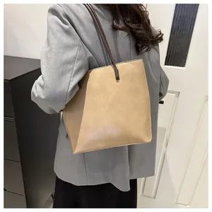 Khaki large capacity tote bag with dark brown straps shown on a model back view