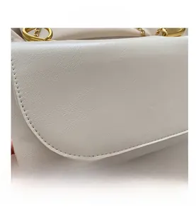Gros plan d'un sac en cuir blanc à motif litchi avec d'élégants détails en métal doré