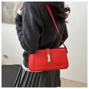 Détail du sac à bandoulière en cuir rouge avec boucle dorée porté par un mannequin