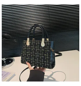 Détail de la texture en tweed noir et doré sur un petit sac à bandoulière chic