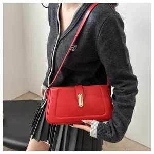 Détail de la texture en cuir rouge mat et du fermoir en métal doré sur le sac à main