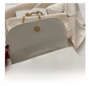 Détail du fermoir magnétique doré et de la texture cuir du petit sac blanc