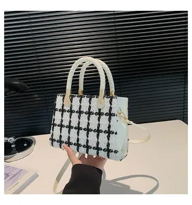 Détail du sac bandoulière en tweed noir et blanc avec poignée tissée et métal doré