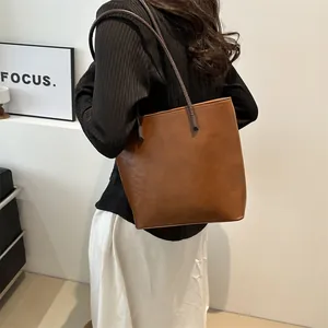 Minimalist brown leather tote bag with long shoulder straps for a casual daily look