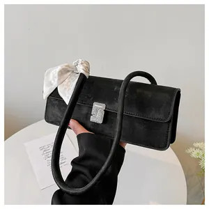 Détail du sac à bandoulière en daim noir avec boucle en strass et foulard en soie décoratif