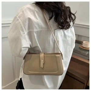 Sac baguette beige à boucle dorée porté en bandoulière pour un style décontracté