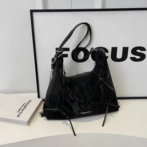 Sac hobo chic en cuir noir brillant avec des nœuds et une bandoulière en chaîne