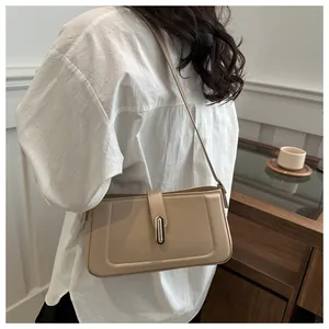 Détail du sac baguette beige clair avec boucle dorée sur silhouette en blanc