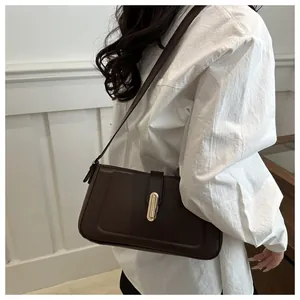 Détail du sac bandoulière marron foncé avec un fermoir rotatif ovale doré chic