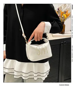 Gros plan d'un sac à main blanc avec logo SM en clous dorés et détails métalliques