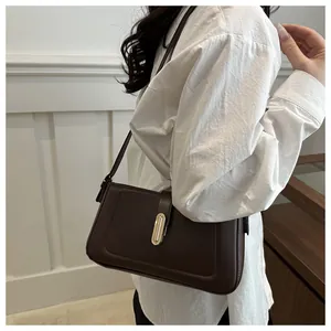 Détail du sac bandoulière marron foncé avec fermoir métallique doré élégant sur modèle