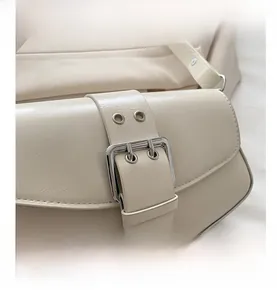 Detail of cream PU leather shoulder bag with silver square buckle and metal eyelets