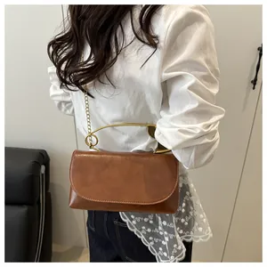 Détail d'un sac vintage marron avec poignée créative en forme d'épingle dorée