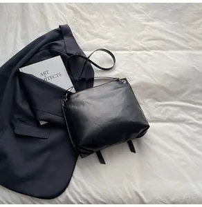 Détail d'un sac cabas en cuir noir mat minimaliste avec de fines lanières sur veste