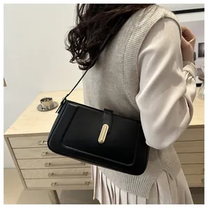 Détail d'un sac porté épaule en cuir noir avec boucle dorée et coutures élégantes