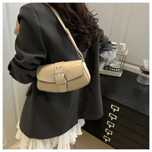 Macro detail of beige retro baguette bag with large silver metal buckle on a shoulder strap