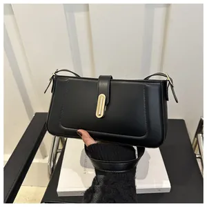 Détail du sac baguette noir minimaliste avec boucle en métal doré et bandoulière en cuir