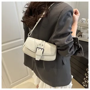 Detail of minimalist cream leather underarm bag featuring a large silver buckle and texture