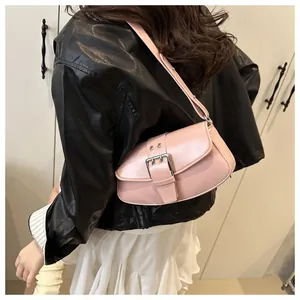 Detail of light pink shoulder bag featuring decorative strap and silver metal buckle