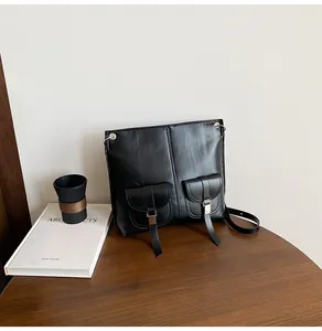 Détail d'un sac à bandoulière en cuir noir avec poches utilitaires et boucles en métal argenté