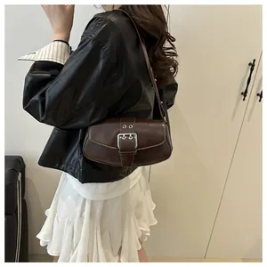 Detail of dark brown leather underarm bag with silver buckle on a stylish model