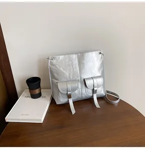 Détail du sac à bandoulière argenté brillant avec poches avant et boucles métalliques
