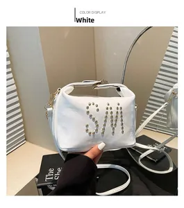 Vue détaillée du sac à main blanc en cuir avec logo en rivets SM et bandoulière dans un miroir