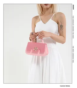 Detail der rosa Handtasche mit goldenem M-Logo und Pailletten-Textur auf weißem Hintergrund