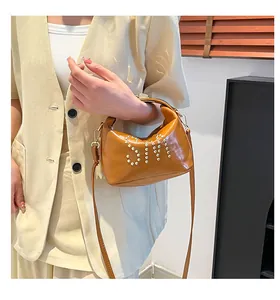 Détail du sac en similicuir caramel avec rivets dorés SIM et bandoulière réglable