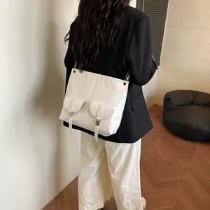 Grand sac cabas blanc en cuir avec poches avant porté par un mannequin pour un style bureau