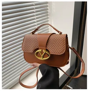 Detalle de bolso vintage marrón con hebilla en V dorada y acabados metálicos finos