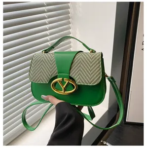 Detalle de bolso de cuero verde con solapa de espiga gris y hebilla en V de metal dorado