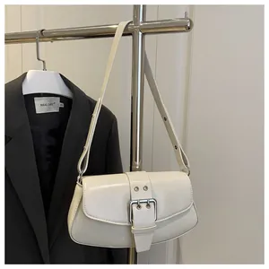 Detail of cream white faux leather baguette bag with silver buckle on a grey suit hanger