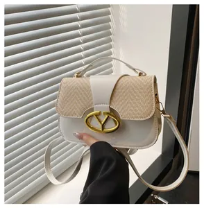 Detalle de bolso de mano de cuero blanco y paja con hebilla ovalada dorada y bandolera