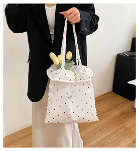 Dettaglio della borsa tote in mesh bianca con ricami floreali neri ed etichetta Fashion