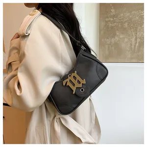 Détail d'un sac bandoulière en cuir noir mat avec logo doré porté par un mannequin