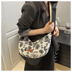 On-body view of large canvas crescent bag with landscape print and fabric shoulder strap