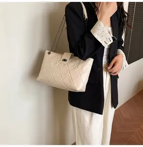 Detail of quilted beige shoulder bag with gunmetal chain strap on model in black blazer