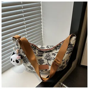 Detail of canvas crescent bag featuring landscape print and panda plush charm with pink flowers
