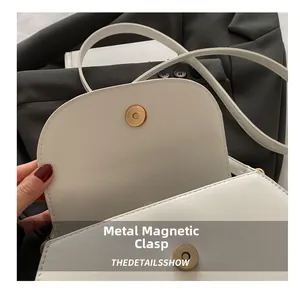 Detailaufnahme einer weißen Ledertasche mit einem goldenen Magnetverschluss-Zylinder